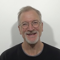 Andrew Powers wears glasses and has a white goatee. 