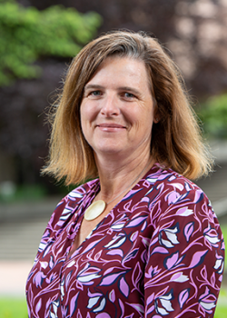 Photo of Julie McCleery who has shoulder length brown hair and wears a magenta-colored floral top. 