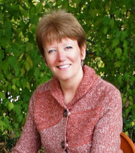 Photo of a smiling woman in front of a leafy background
