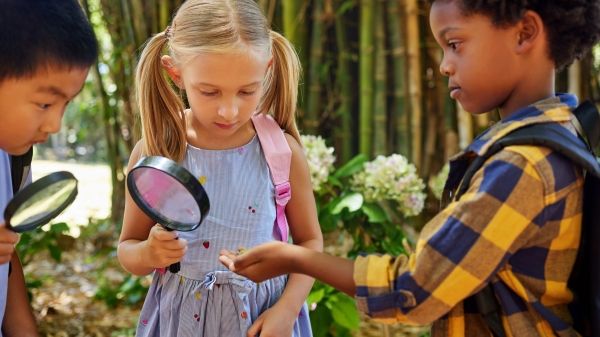 Three students holding magnifying glasses