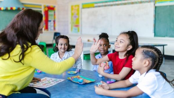 Teacher high-fiving four smiling students