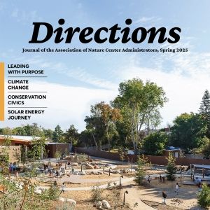 The cover of the Directions journal: A photo of children playing outdoors amid a winding path and sparse, desertous plants. In the background, a building stands amid trees.