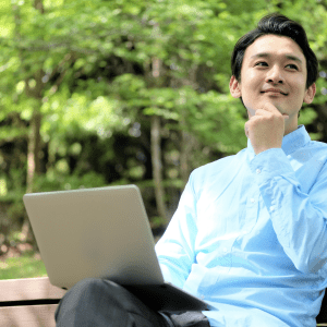 Person on bench, trees in background, laptop.