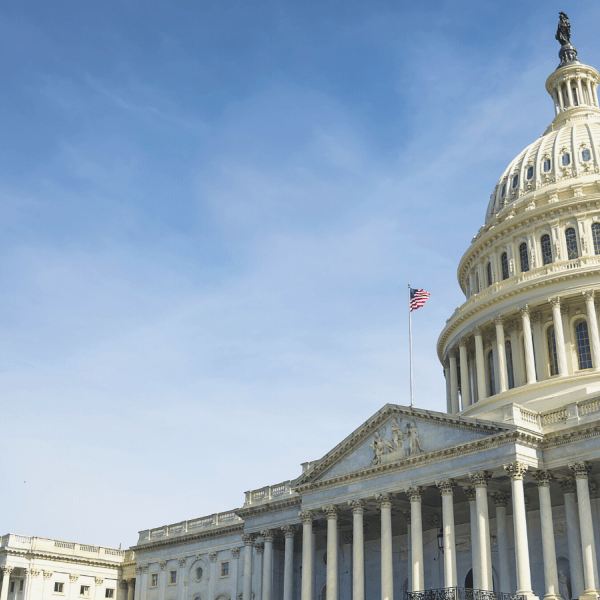 Image of the United States Capitol. The building fits in the bottom right side of the image, while a blue sky with light clouds rises up behind it. 